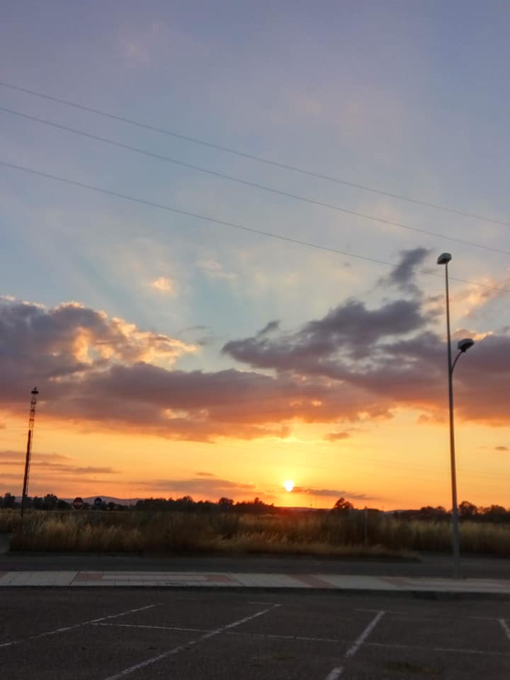 Atardecer anaranjado con rayos de sol entre las nubes sobre un campo