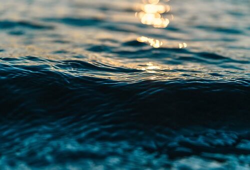 Primer plano de una ola de mar con reflejos dorados del atardecer desenfocados
