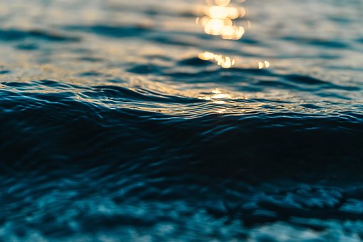 Primer plano de una ola de mar con reflejos dorados del atardecer desenfocados