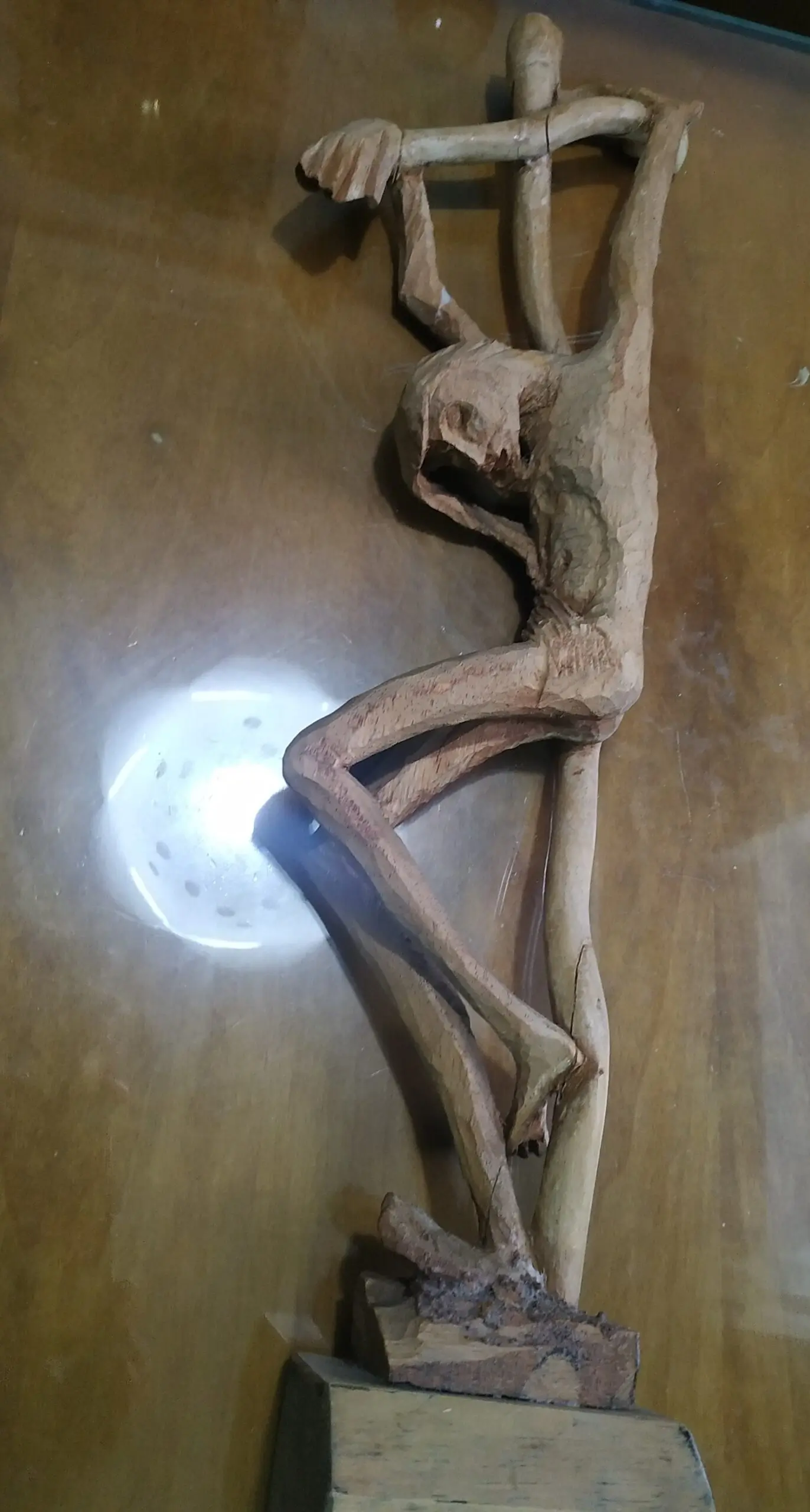 Talla de madera de un Cristo crucificado, con las piernas cruzadas y expresión de dolor