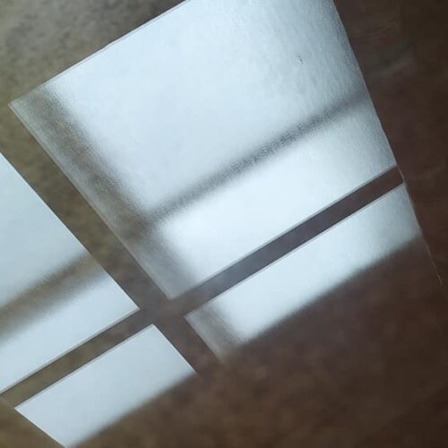 Reflejos de luz en forma de rombos sobre una superficie de madera, entrando por una ventana