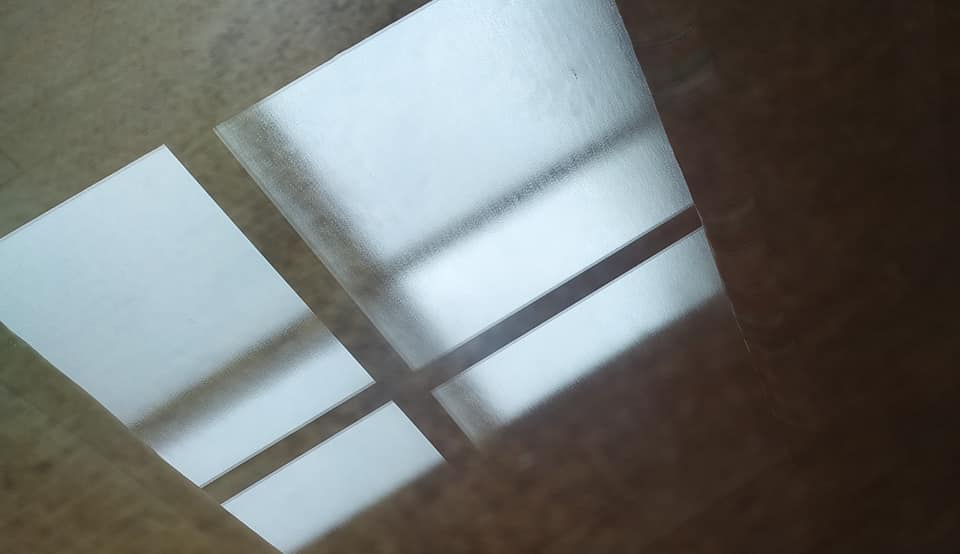 Reflejos de luz en forma de rombos sobre una superficie de madera, entrando por una ventana