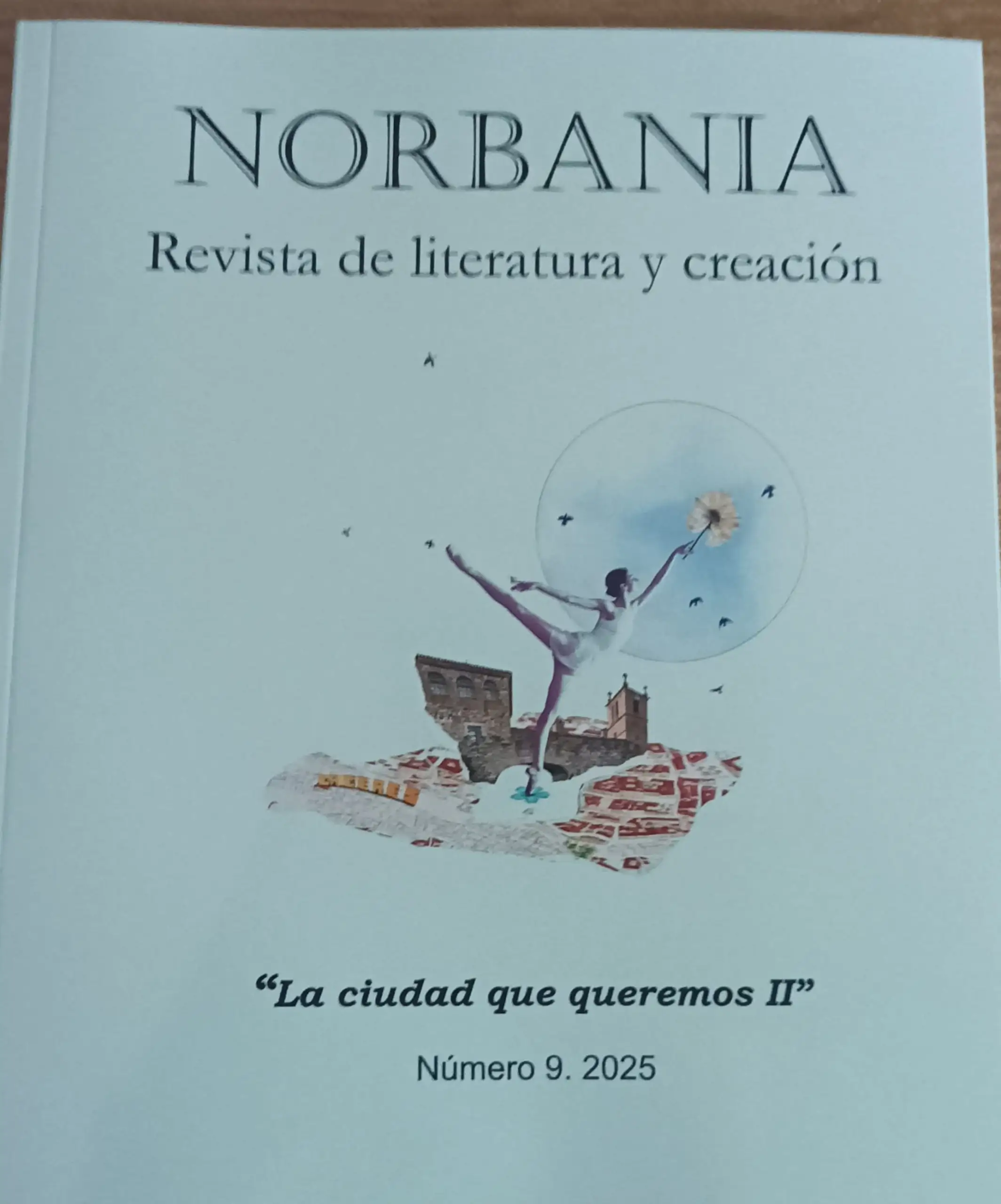Portada de la revista Norbania, número 9 de 2025, "La ciudad que queremos II", con una ilustración de una bailarina sobre un mapa de Cáceres